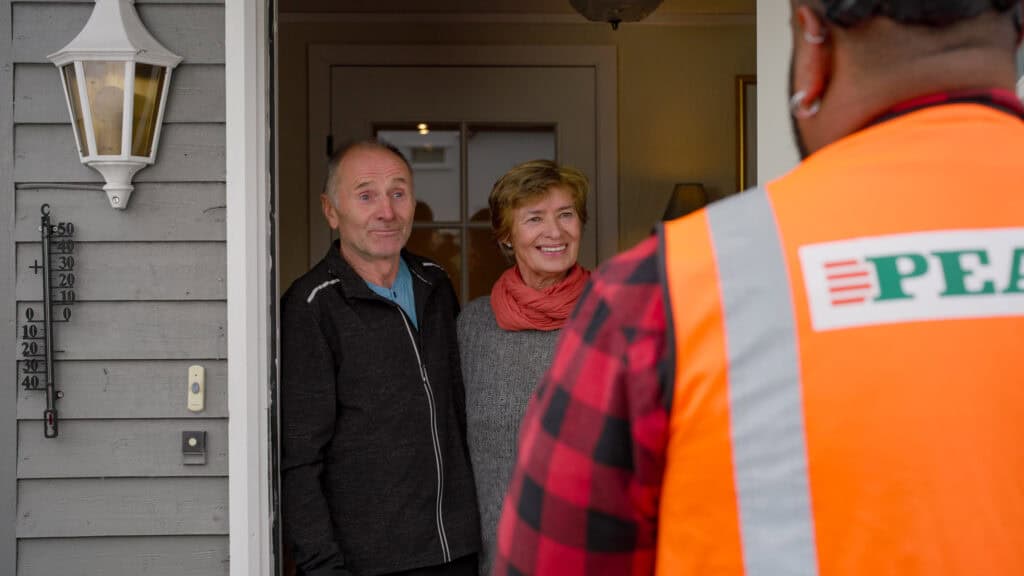 Scene fra reklamefilm for PEAB. Bildet viser to eldre beboere som får overrasket får besøk på døren.