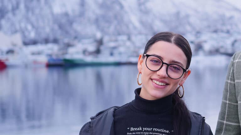 Bildet av Sofia hos Glø, hun smiler. Tromsøsundet er i bakgrunnen.